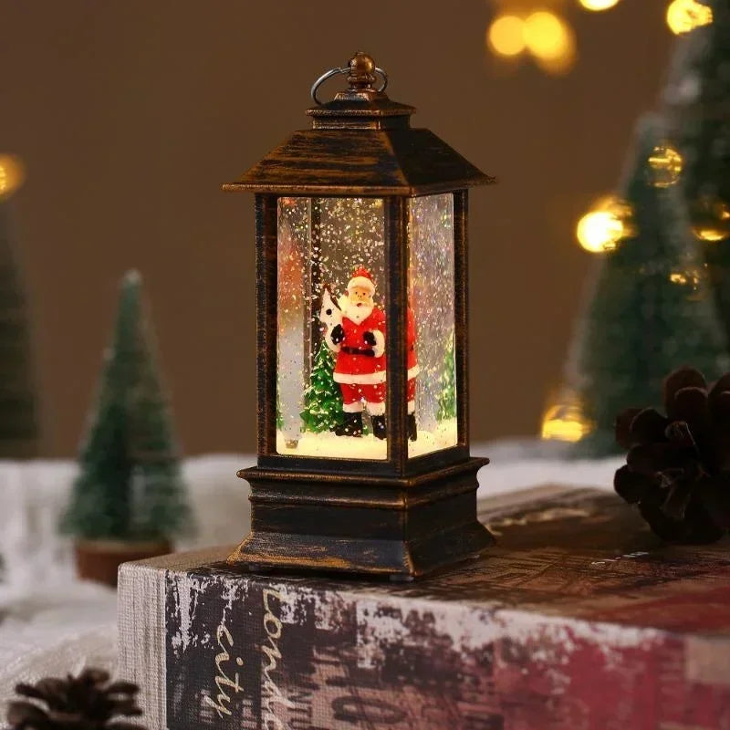 A small dark bronze lantern with a Santa Claus snow globe inside, placed on top of a book with blurred Christmas trees and warm lights in the background.
