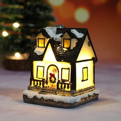Decorative house-shaped light with snow on the roof, glowing warmly against a blurred background.