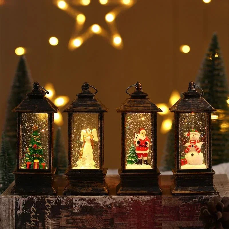 Four black lantern-shaped decorative snow globe lights with holiday scenes inside, displayed on a rustic wooden surface with warm string lights and blurred Christmas trees in the background.