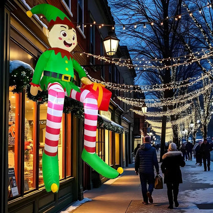 TK-H Merchandise 8ft inflatable sitting elf decoration with LED lights displayed outside a festive storefront.